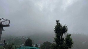 A building with a balcony, surrounded by trees and a foggy landscape.