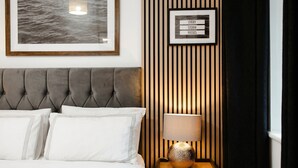 A bedroom with a tufted headboard, a framed quote on the wall, a bedside lamp, and a framed picture above the bed. - Boutique apartment near Old Trafford · terrace · sleeps 6 (Greater Manchester)