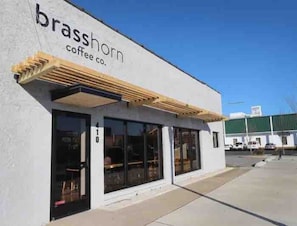 Un edificio con un cartello che recita 'brasshorn coffee co.' e ampie vetrate.
