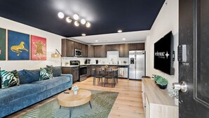 A modern living room with a blue sofa, a coffee table, and artwork on the wall. - NEW ~ Charming, Cozy Apt DWTN Murfreesboro, TN (Murfreesboro)