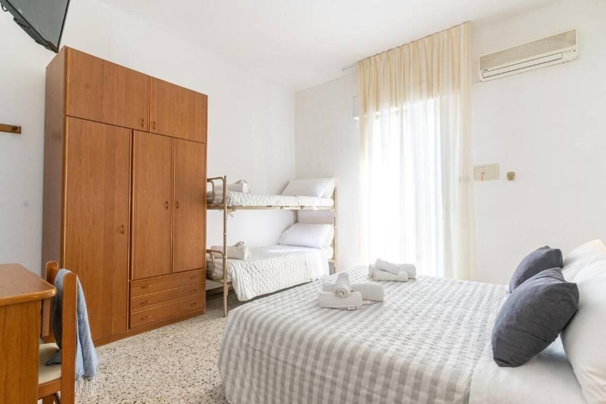Ein Schlafzimmer mit Etagenbett, Holzschrank, Schreibtisch und einem Bett mit Kissen.
