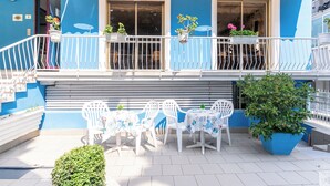 A blue building with a balcony, white chairs, and tables. - Hotel Lariana (Rimini)