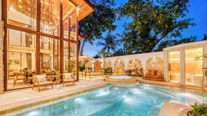 Un área de piscina moderna con hidromasaje, mobiliario exterior y una escalera que conduce a un nivel superior.