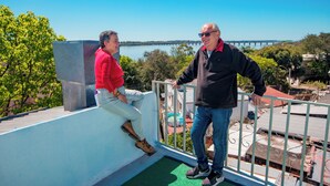 Deux personnes sur un balcon, avec vue sur un pont et sur l’eau.