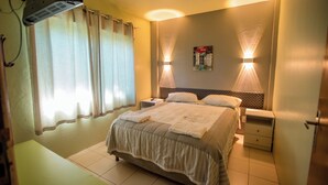 Une chambre d’hôtel avec un lit, des tables de chevet, des rideaux et des lampes fixées au mur.
