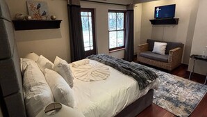 A bedroom with a bed, a TV, a sofa, and a small table. - Room-starling Room - Staynest Guesthouse (Johannesburg)