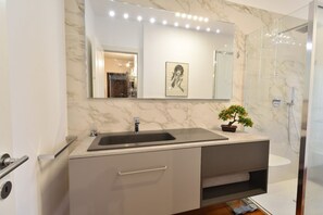 Une salle de bain moderne avec un lavabo en marbre, un grand miroir et une douche.
