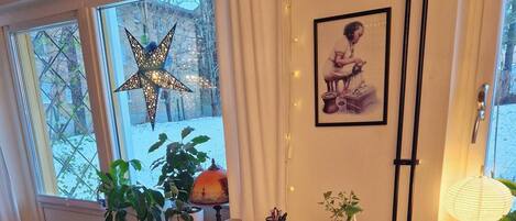 A wooden dining table with chairs, a star decoration, potted plants, and a framed picture on the wall.