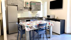 Una cocina compacta con refrigerador, microondas y salpicadero de azulejos.