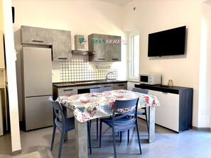 Eine kompakte Küche mit Kühlschrank, Mikrowelle und einer gefliesten Spritzschutzwand.