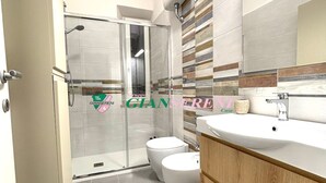Un baño moderno con ducha, inodoro y tocador.