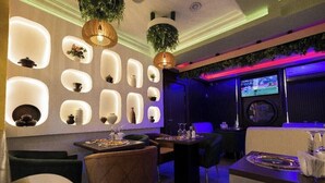 Un comedor moderno con iluminación empotrada, plantas colgantes y una pantalla de televisión.