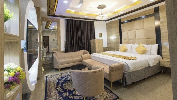 Un dormitorio moderno con una cama grande, un sofá, una silla y un espejo.