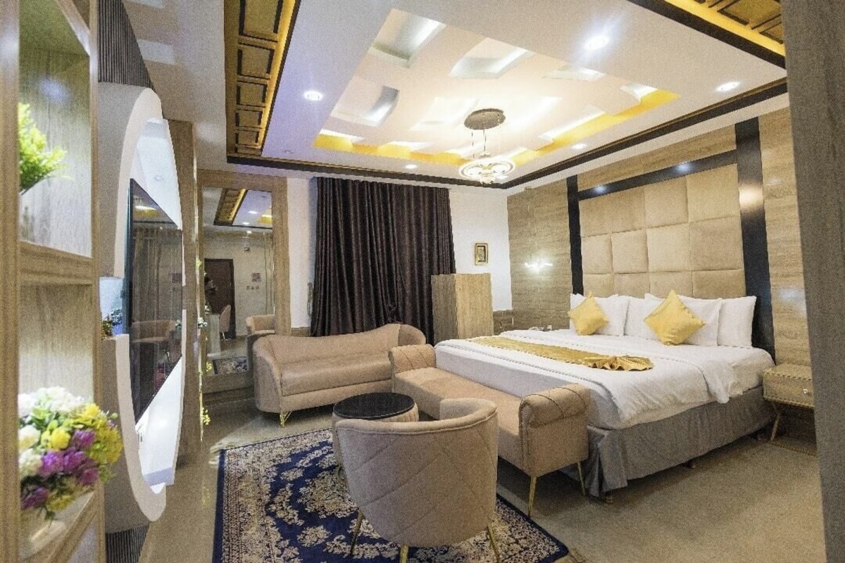 A modern bedroom with a large bed, a sofa, a chair, and a mirror.