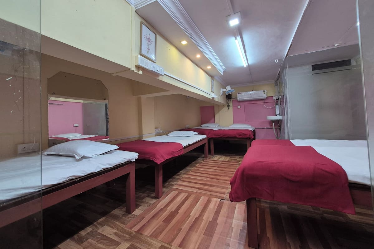 Una habitación con literas, suelo de madera, un espejo y un aire acondicionado instalado en la pared.