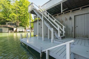 Un muelle con una escalera que lleva a un edificio de fachada de madera y una puerta.