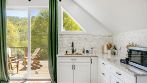 Een keuken met witte kastjes, een magnetron en uitzicht op een balkon met tuinmeubilair.