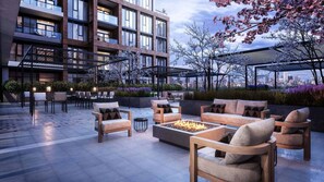Een dakterras met zitplaatsen buiten, een vuurplaats en uitzicht op de skyline van de stad.