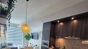 A modern kitchen with dark wood cabinets, stainless steel appliances, and a glass dining table with chairs. - Luxury Executive 1+Den | Office | Pool, Gym, Sauna | Free Parking (Toronto)