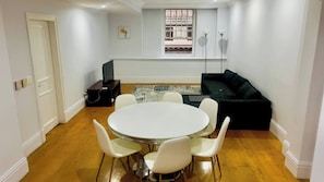 A room with a round table and chairs, a black sofa, a window with a view, and a door. - Cape Town Inner City Stay (Cape Town)