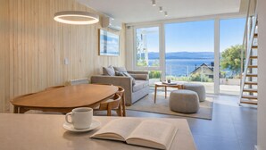 Un soggiorno moderno con pavimento in legno, un tavolo da pranzo con sedie, un divano, un tavolino da caffè e un libro sul tavolo.