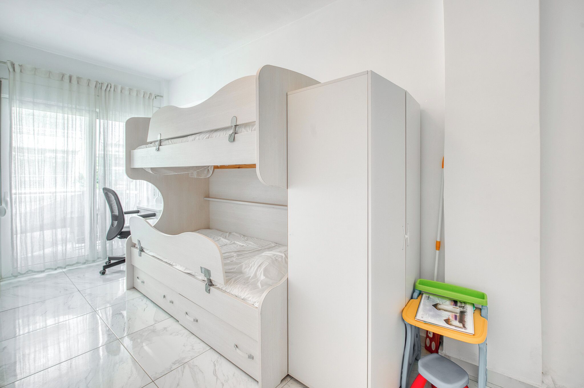 A bedroom with a bunk bed, a desk, and a chair.