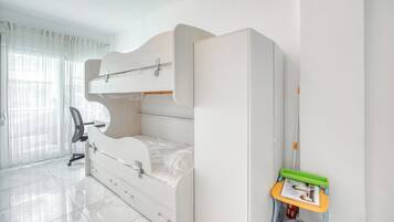 A bedroom with a bunk bed, a desk, and a chair.