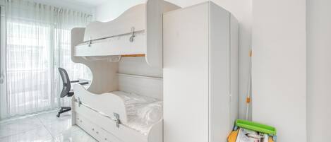 A bedroom with a bunk bed, a desk, and a chair.