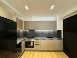 Una cocina moderna con un refrigerador negro, una estufa negra, un lavaplatos y gabinetes de colores claros.