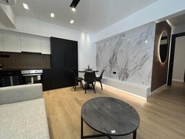 Un interior moderno con comedor, sofá, pared de mármol y cocina.