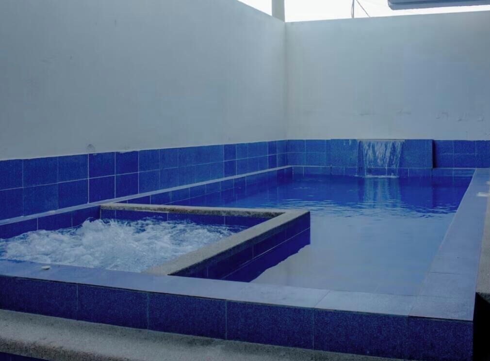 Une piscine aux carreaux bleus et un espace équipé d’un jacuzzi.