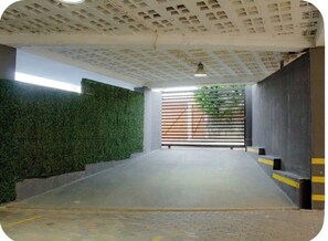 Ein überdachter Parkbereich mit Betonboden, grüner Wand und Metallgitter.