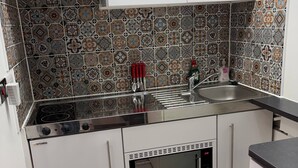 Een kleine keuken met een magnetron, fornuis en oven.