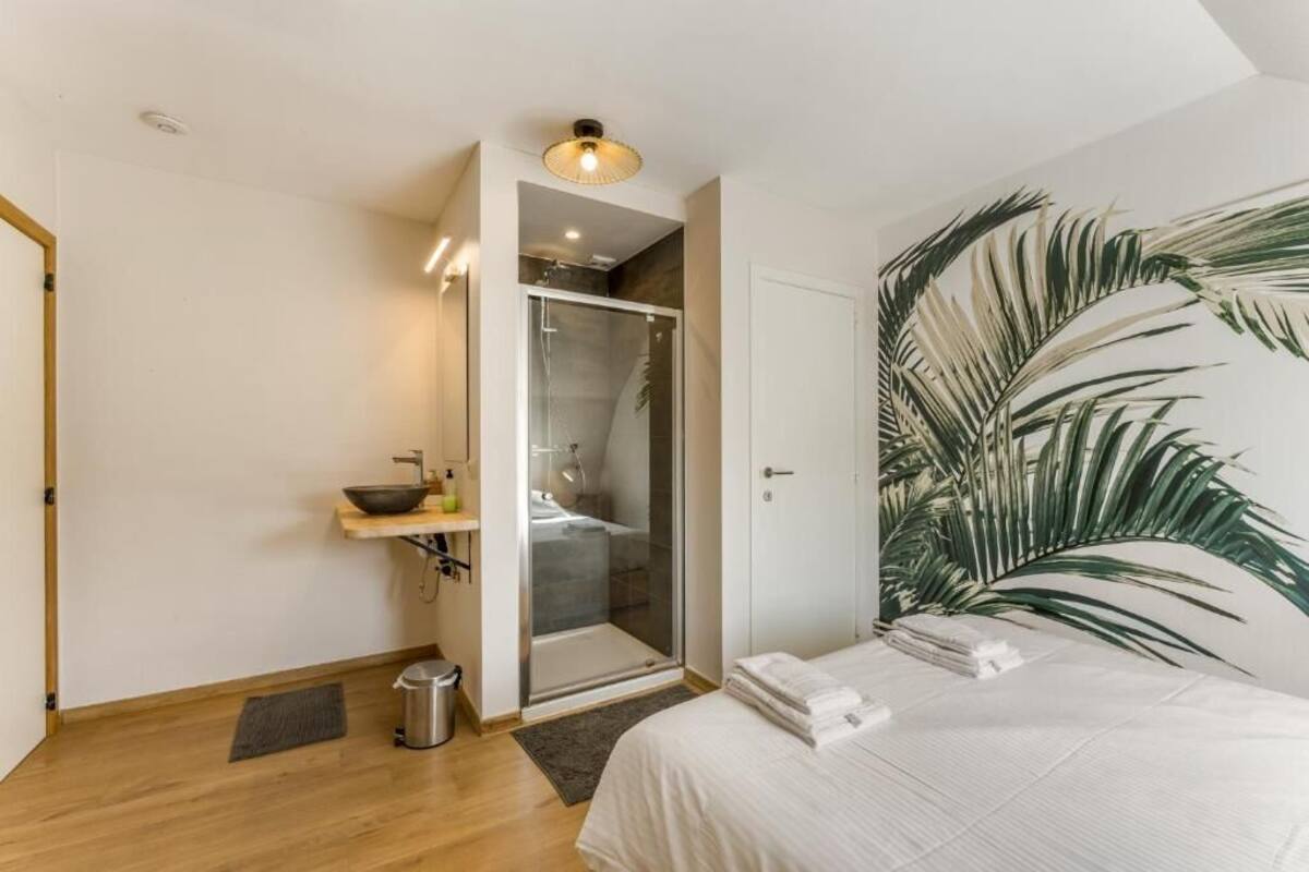 Une chambre avec un lit, une douche et une grande fresque murale représentant un palmier.