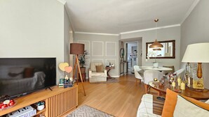 Een woonkamer met een televisie, bank en een eethoek.