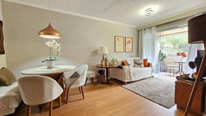 Een moderne woonkamer met een ronde eettafel, twee stoelen, een bank, een salontafel en een hanglamp.