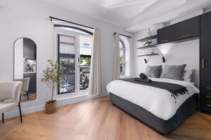A modern bedroom with a large bed, a desk, and a view through a sliding door. - Chic Valour studio in De Waterkant (Cape Town)