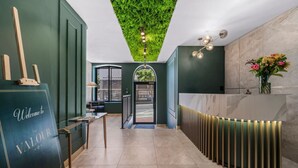 Un'area reception con parete verde, una scrivania per gli ospiti, un punto luce a parete e una porta che dà all'esterno.