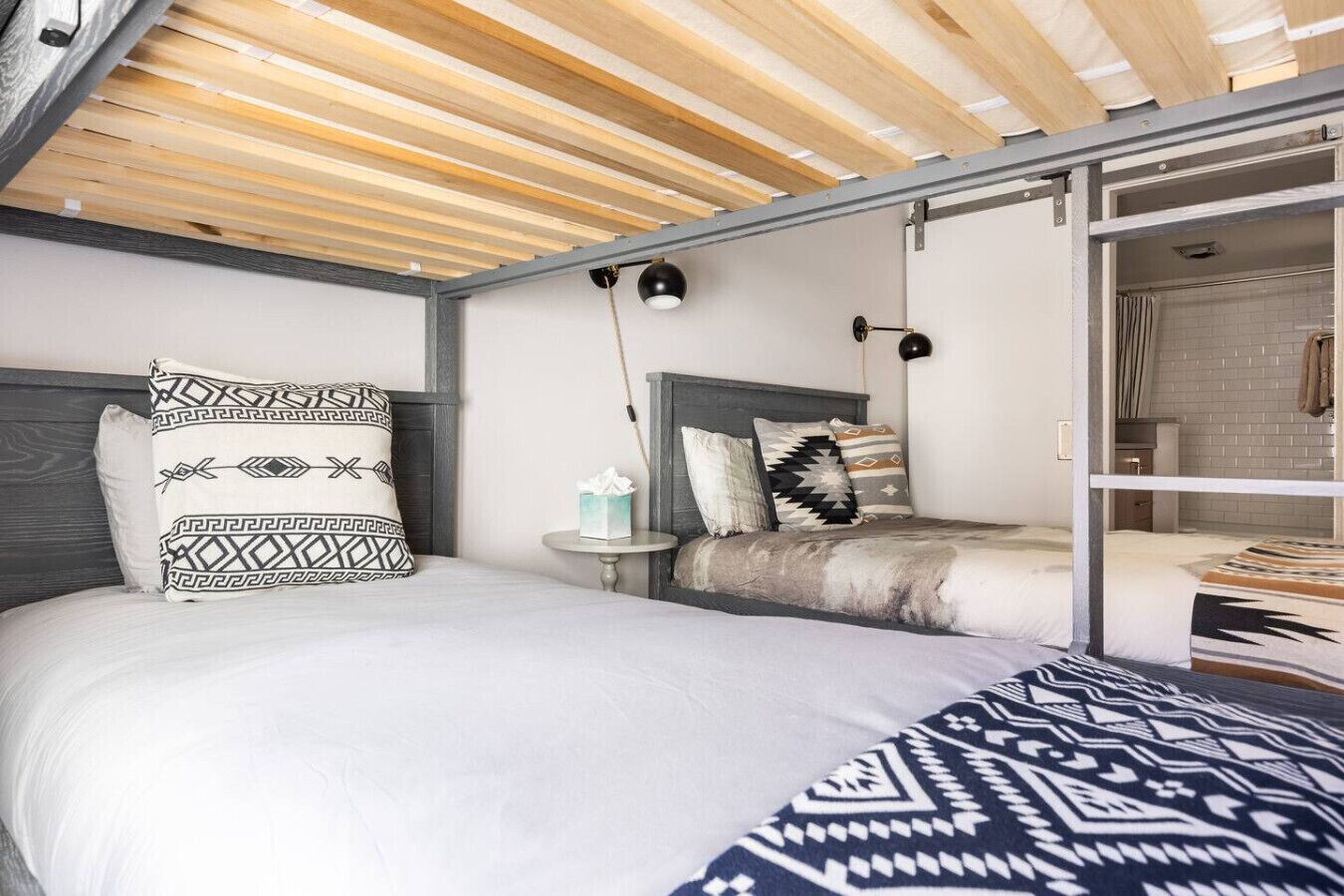 A room with a bed, bedside table, and a view of a bathroom.