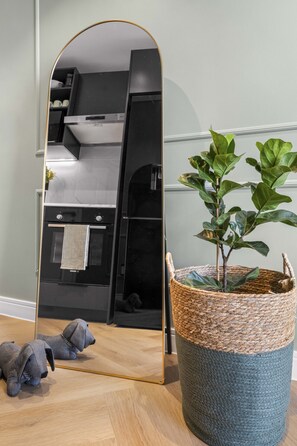 A modern kitchen with a black countertop, a stainless steel range hood, and a large mirror reflecting the kitchen. - Corner Suite The Valour in De Waterkant (Cape Town)