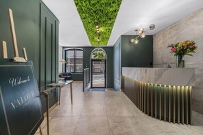 A reception area with a green wall, a reception desk, a seating area, and a ceiling with a green, grass-like design. - Corner Suite The Valour in De Waterkant (Cape Town)