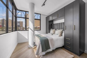 A modern bedroom with a large bed, built-in wardrobe, and a city view. - Corner Suite The Valour in De Waterkant (Cape Town)
