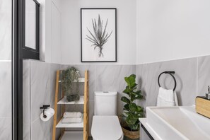 A modern bathroom with a toilet, sink, and shelves with plants. - Corner Suite The Valour in De Waterkant (Cape Town)