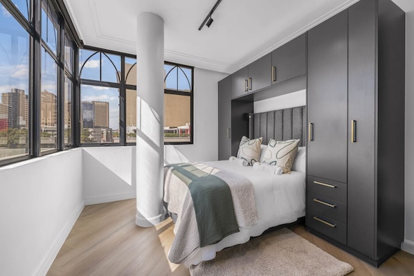 A bedroom with a large window, a bed, and a wardrobe. - Corner Suite The Valour in De Waterkant (Cape Town)