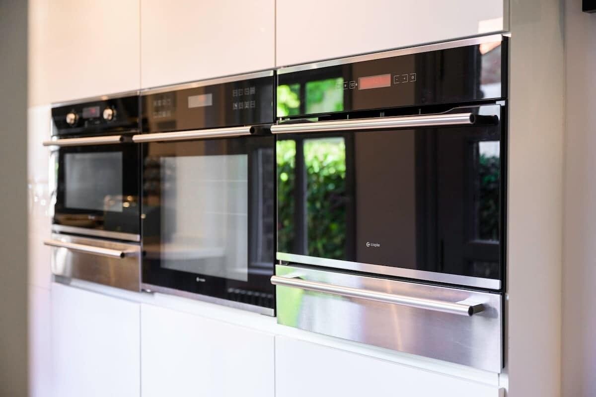 Une cuisine équipée d’appareils électroménagers intégrés, notamment un four à micro-ondes, un four et un réfrigérateur.