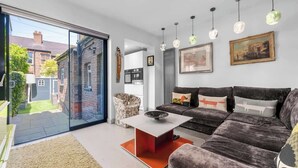 Ein modernes Wohnzimmer mit einer Couch, einem Couchtisch und einer Glastür, die in einen Garten führt.
