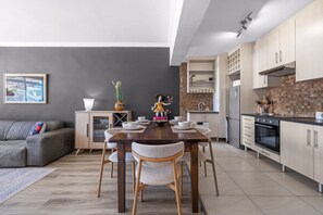 Een moderne keuken met een eethoek, grijze muren en een grijze bank.