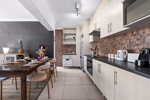 Een moderne keuken met een eethoek, met een donkere wand, betegelde spatwand en moderne apparatuur.