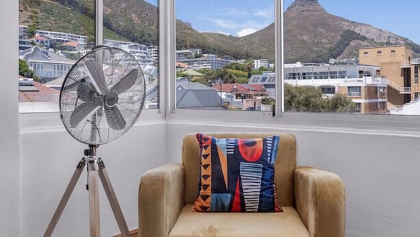 Ein Zimmer mit großem Fenster, einem Ventilator und einem Sessel.