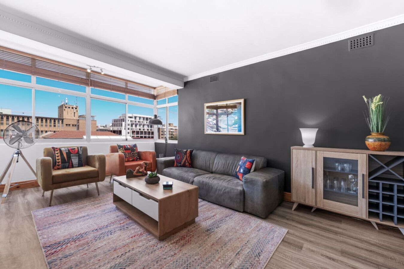A modern living room with a sofa, armchairs, a coffee table, and a cabinet.